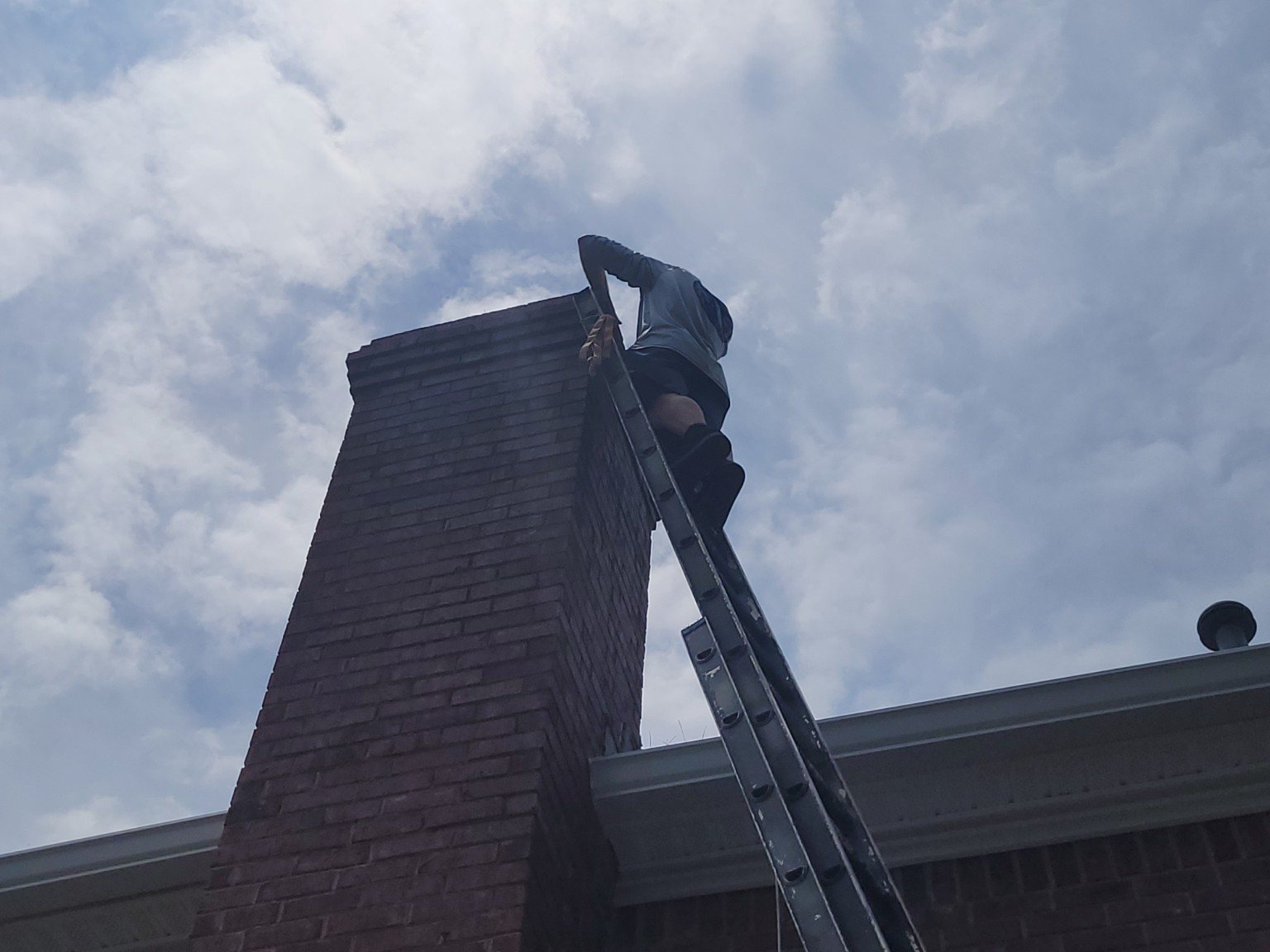 Technician working from a lift beside a chimney